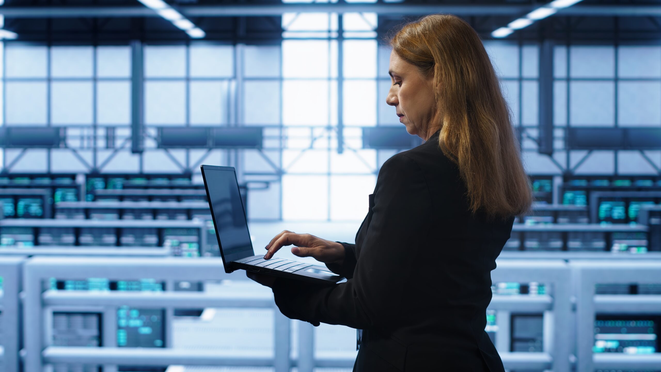 IT specialist in server hub monitoring server infrastructure using notebook